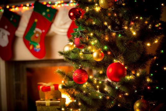 A decorated Christmas tree with ornaments and lights, set in a room with a fireplace and holiday decorations.